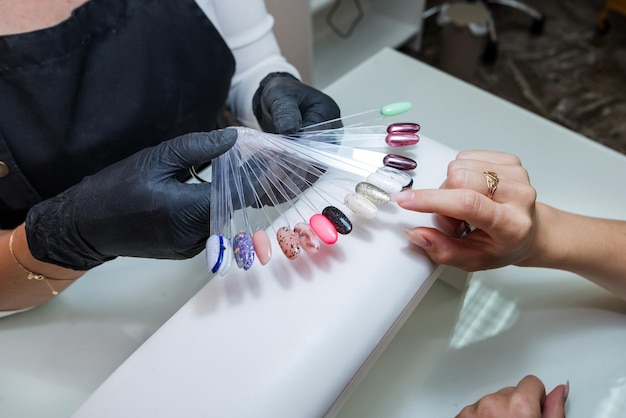 Choix de la couleur des ongles Une jeune fille choisit la couleur de ses ongles dans un salon de beauté Beauté et santé des ongles Manucure et client dans un salon de manucure