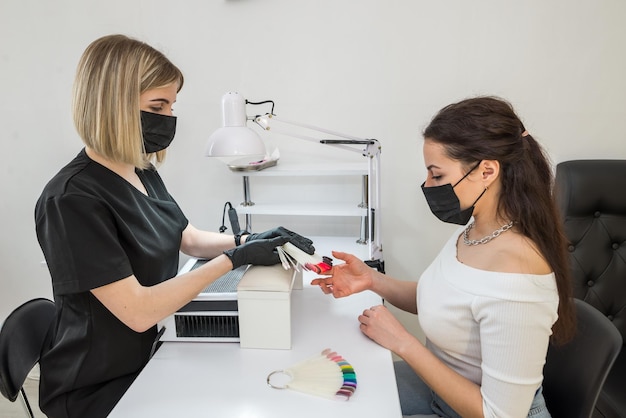 Choix de la couleur des ongles Une jeune fille choisit la couleur de ses ongles dans un salon de beauté Beauté et santé des ongles Manucure et cliente dans un salon de manucure