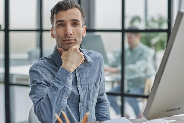 Un choix difficile a embarrassé un jeune homme assis à une table au bureau avec un ordinateur portable