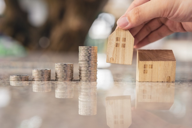 Choix de main mini modèle de maison en bois à partir du modèle et de la ligne de monnaie sur table en bois