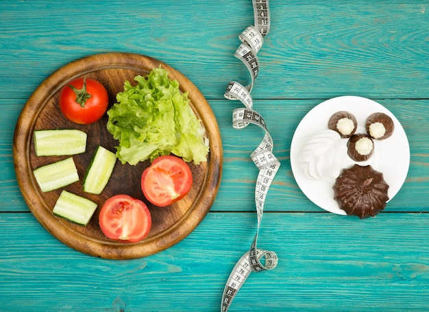 Photo choix de régime alimentaire sur légumes ou gâteaux et bonbons et ruban centimétrique