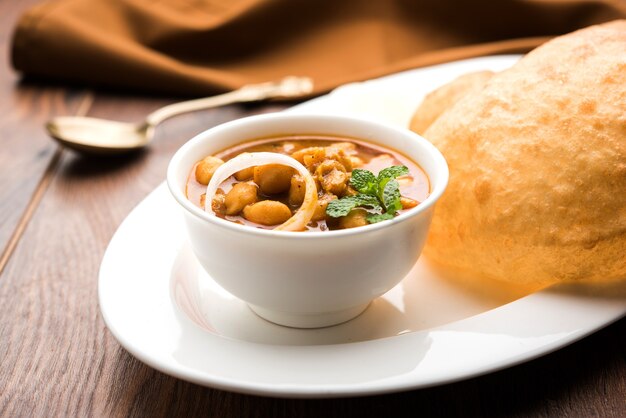 Chole Bhature ou curry de pois chiches et Puri frit servis dans de la vaisselle en terre cuite sur fond blanc. mise au point sélective