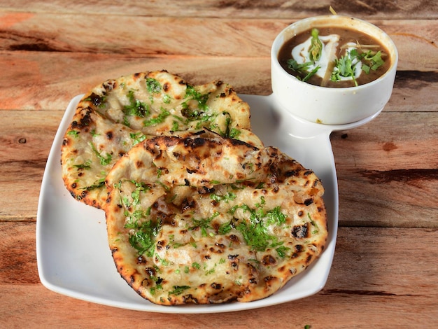 Chole Kulcha Clay naan farci cuit au four servi avec du channa masala ou du chole masala repas typique d'Amritsar Inde isolé sur un fond en bois rustique mise au point sélective