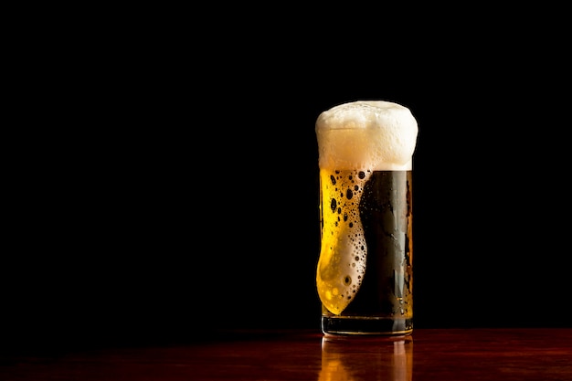 Chope de bière [bière] sur fond sombre, verre givré de bière légère.