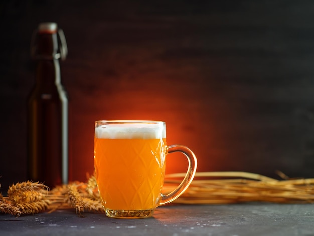 Une chope de bière de blé traditionnelle sur un tableau sombre une bouteille de bugel épis de blé rétroéclairage coloré