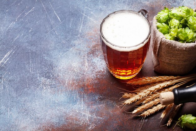 Chope de bière blonde houblon et blé sur une vieille table en pierre