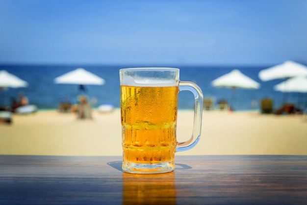 Chope de bière froide avec de la mousse sur la table.