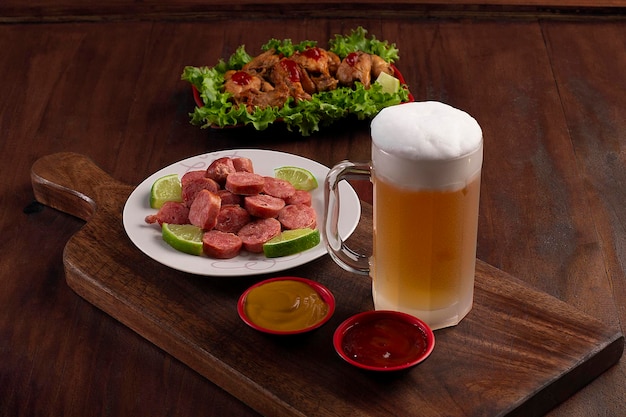 Chope de bière sur planche de bois avec portion de saucisse et poulet frit