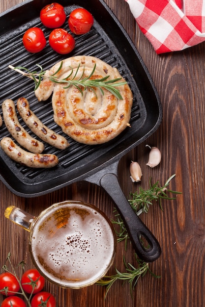 Chope de bière et saucisses grillées sur table en bois. Vue de dessus