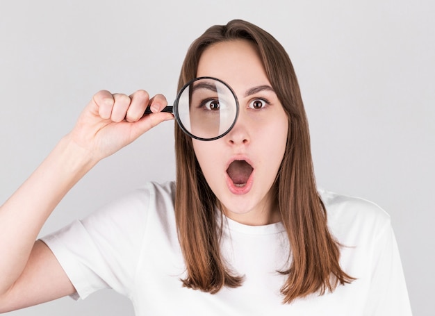 Choqué femme regardant à travers une loupe