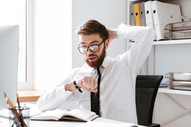 Choqué jeune homme d'affaires en regardant la montre.