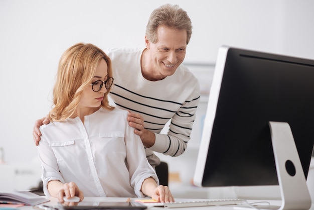 Choqué, jeune secrétaire plein de ressentiment assis au bureau et travaillant sur le projet tout en exprimant son indignation envers le flirt du patron