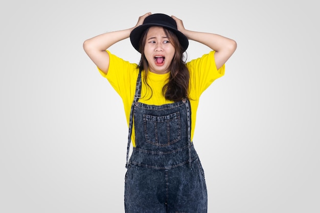 Choqué jolie fille asiatique au chapeau jaune et noir avec un fond blanc