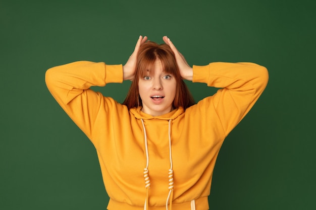 Choqué. Portrait de femme caucasienne isolé sur vert avec fond