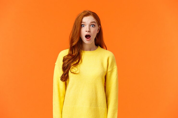 Photo choqué rousse mignonne femme baisse la mâchoire stupéfaite et sans voix, regarde les yeux de la caméra