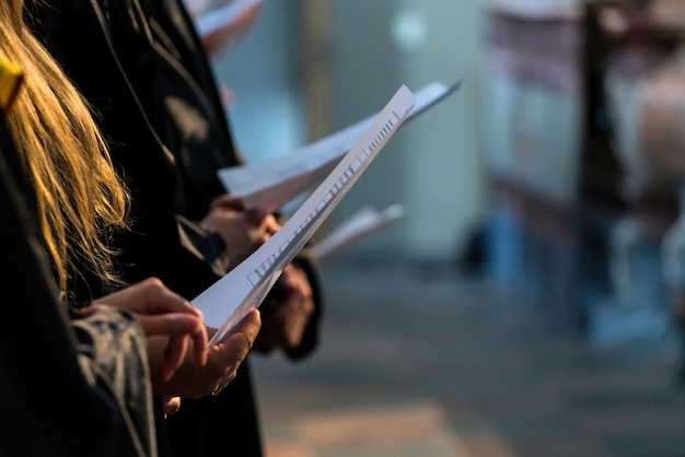 Choristes tenant une partition musicale et chantant le jour de la remise des diplômes des étudiants.