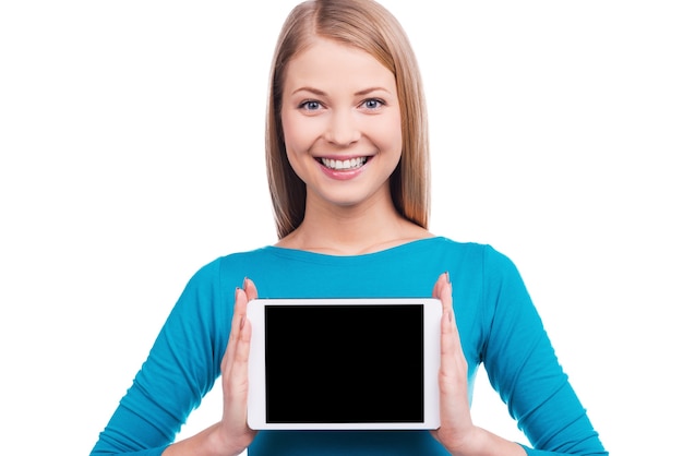 La chose la plus utile. Belles jeunes femmes tenant une tablette numérique et souriant en se tenant debout sur fond blanc.