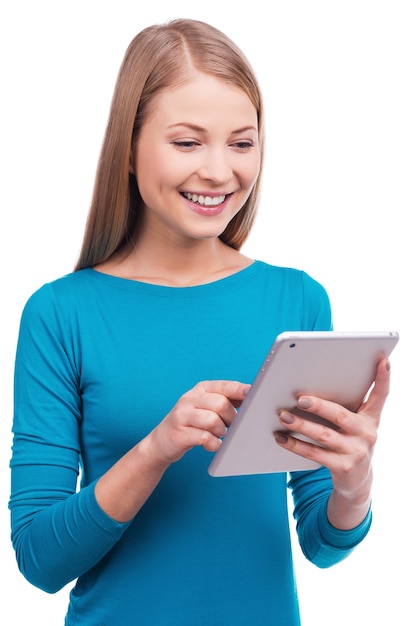 Chose qui est toujours avec moi. Belles jeunes femmes tenant une tablette numérique et souriant en se tenant debout sur fond blanc.