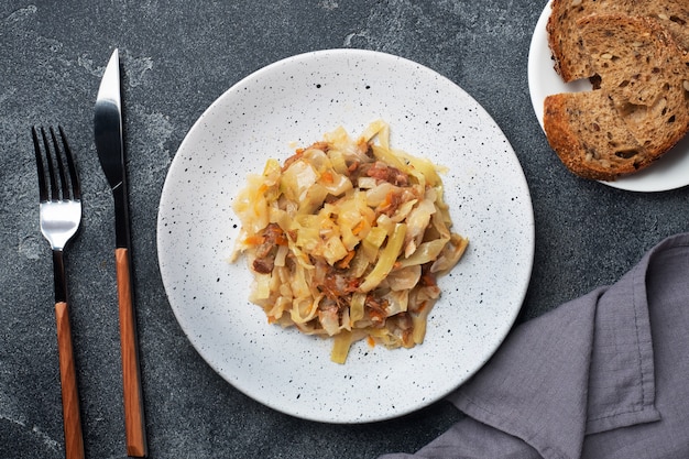 Chou cuit avec de la viande sur une assiette. Fond de béton foncé.