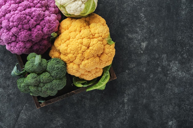 Chou-fleur coloré Diverses sortes de chou-fleur sur un vieux fond de béton gris foncé Choux de couleur violet jaune blanc et vert Brocoli et Romanesco Récolte agricole Maquette