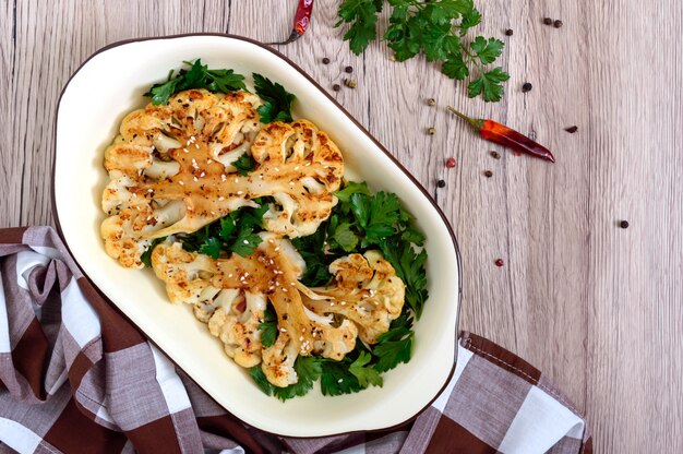 Chou-fleur cuit au four avec des verts sur une table en bois