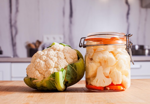 Le chou-fleur frais et fermenté dans un pot sur une table en bois dans la cuisine