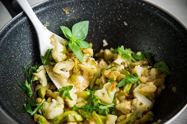 Chou-fleur frit avec courgettes et légumes dans une poêle aux herbes