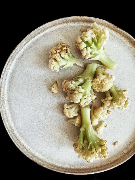 chou-fleur grillé sur une assiette sur fond noir