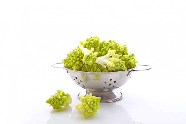 Chou-fleur Romanesco dans une passoire en métal sur fond blanc