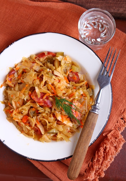 Choucroute aux oignons saucisses et carottes dans une assiette blanche