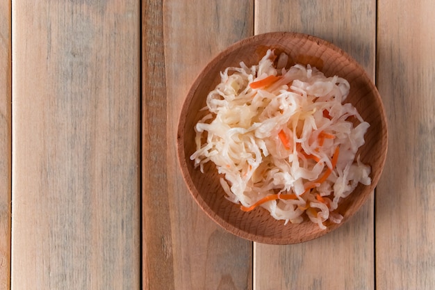 Choucroute maison sur une plaque en bois. Chou fermenté à la carotte sur fond clair