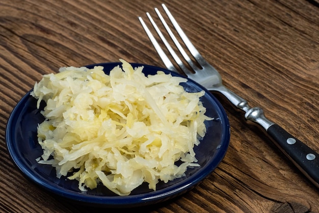 Choucroute marinée maison dans un bol avec une fourchette sur une planche de bois