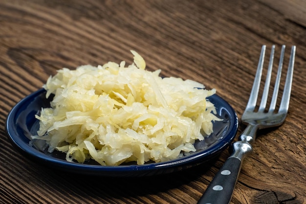 Choucroute marinée maison dans un bol avec une fourchette sur une planche de bois