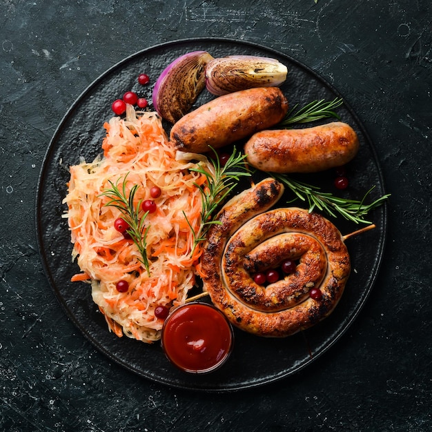 Choucroute et saucisses grillées au romarin et canneberges sur une plaque noire Plat allemand traditionnel Vue de dessus Sur un fond de pierre noire