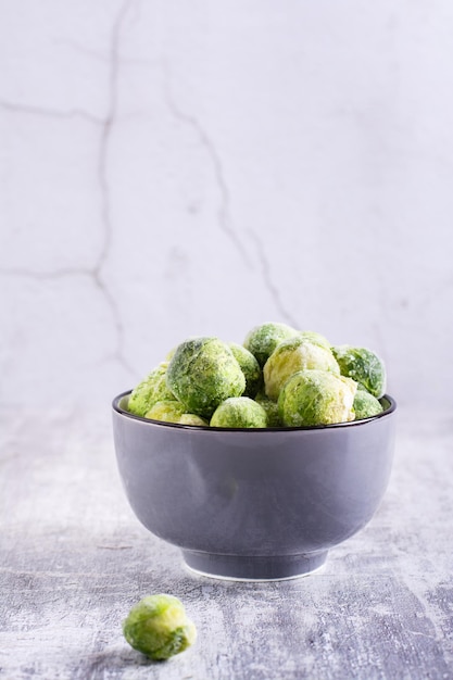 Choux de Bruxelles congelés dans un bol sur fond gris Nourriture végétarienne Vue verticale