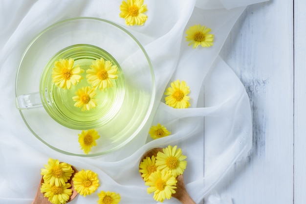 Chrysanthème chaud dans une tasse sur un tissu blanc et bois blanc