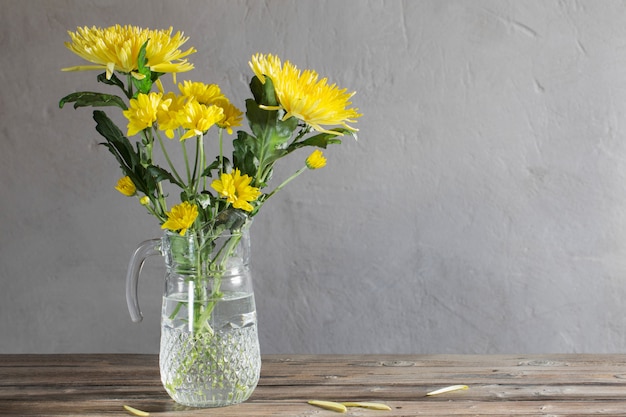 Chrysanthème jaune dans une cruche en verre sur une table en bois