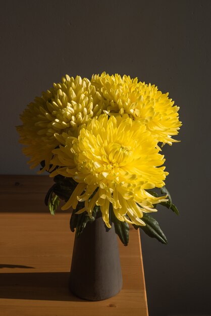 Chrysanthème jaune sur une table libre de beaux chrysanthèmes lumineux fleurissent avec des ombres murales chrysanthème vertical