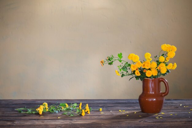 Chrysanthèmes dans un vase sur la vieille table en bois