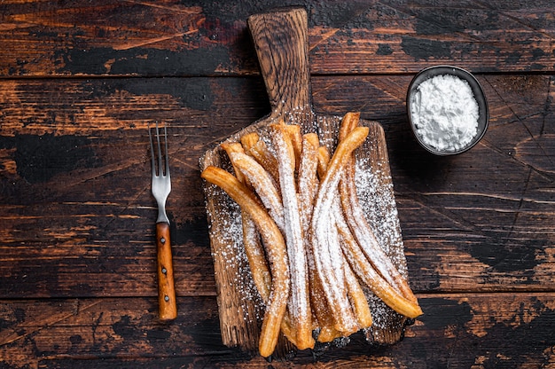 Churros dessert espagnol avec du sucre en poudre sur un plateau en bois