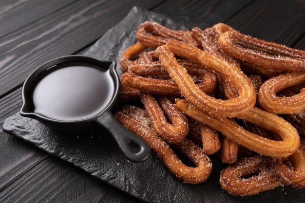 Churros faits maison avec du chocolat sur un fond rustique en bois foncé