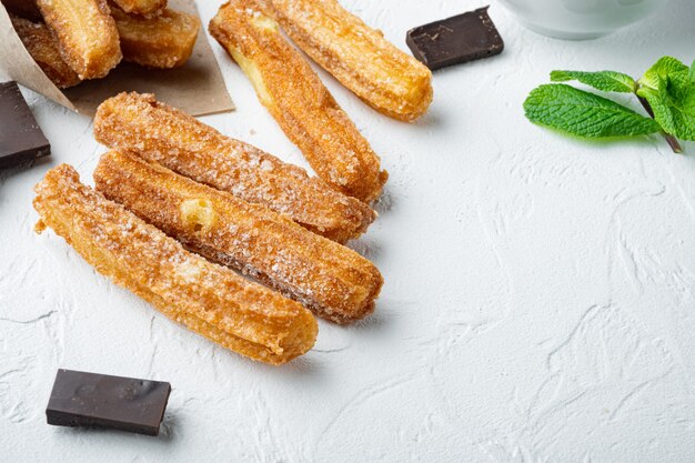 Churros typiques espagnols, pâte frite pâtisserie servie généralement avec sauce piquante au caramel au chocolat, sur table blanche, copyspace