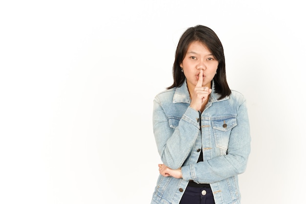 Chut, soyez tranquille de la belle femme asiatique portant une veste en jean et une chemise noire isolée sur blanc