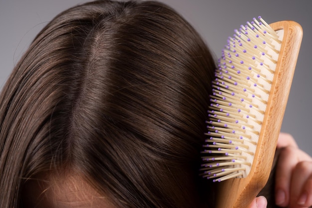 Chute de cheveux de perte de cheveux de plan rapproché dans le problème d'effort de brosse à cheveux de la femme avec un peigne