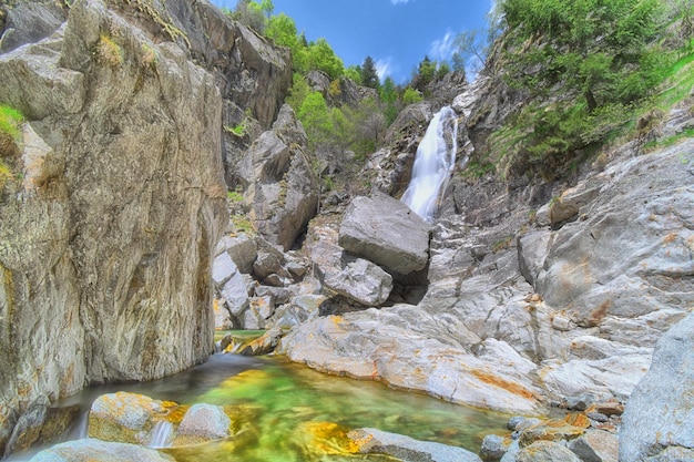 Une chute d'eau dans les montagnes avec un ciel bleu derrière elle