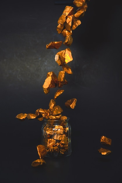 Chute de pépites d'or, de minerai d'or et de bocal en verre