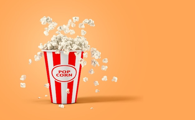 Chute de pop-corn dans une boîte isolée sur fond orange avec espace de copie