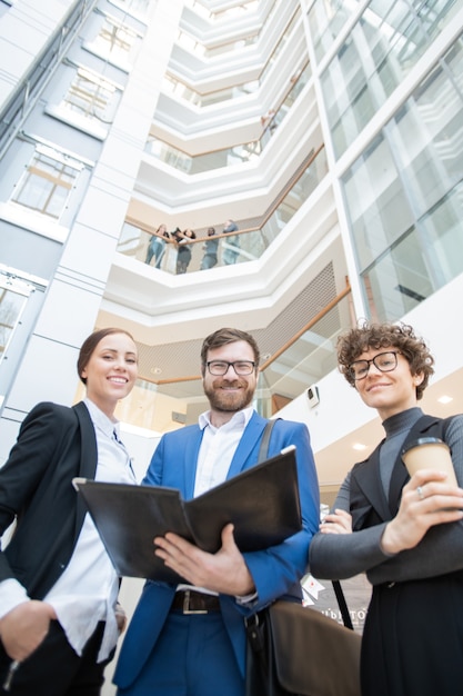 Ci-dessous la vue de jeunes collègues de bureau positifs de visualisation des documents dans le dossier ensemble dans le hall