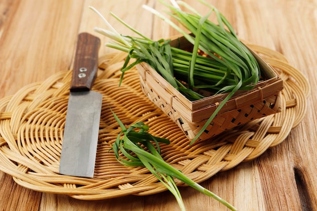 Photo ciboulette chinoise fraîche ou kui chai kucai attachez une corde sur une table en bois