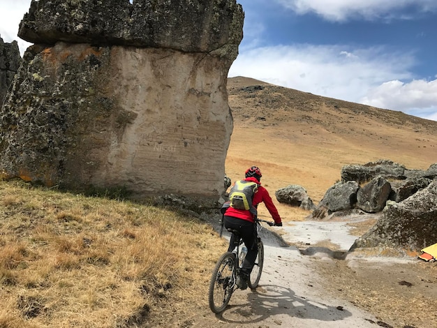 ciclista de espaldas alejandose por un camino entre rocas